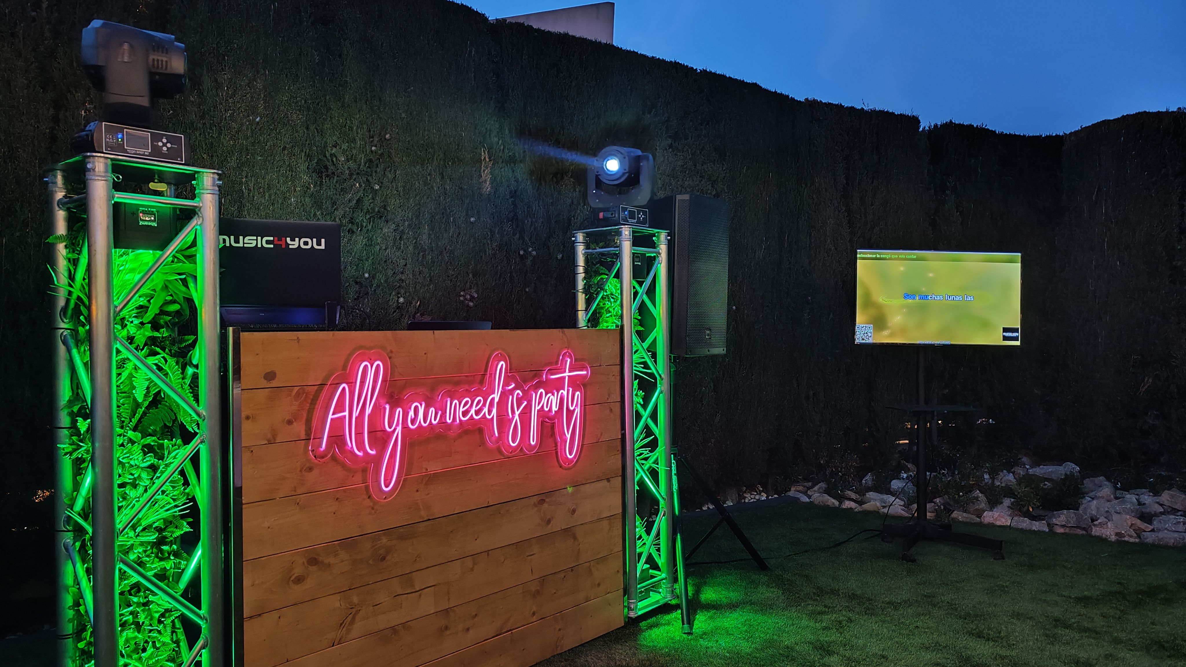 Montaje de DJ al aire libre con neón «All you need is party», luces verdes y pantalla de karaoke