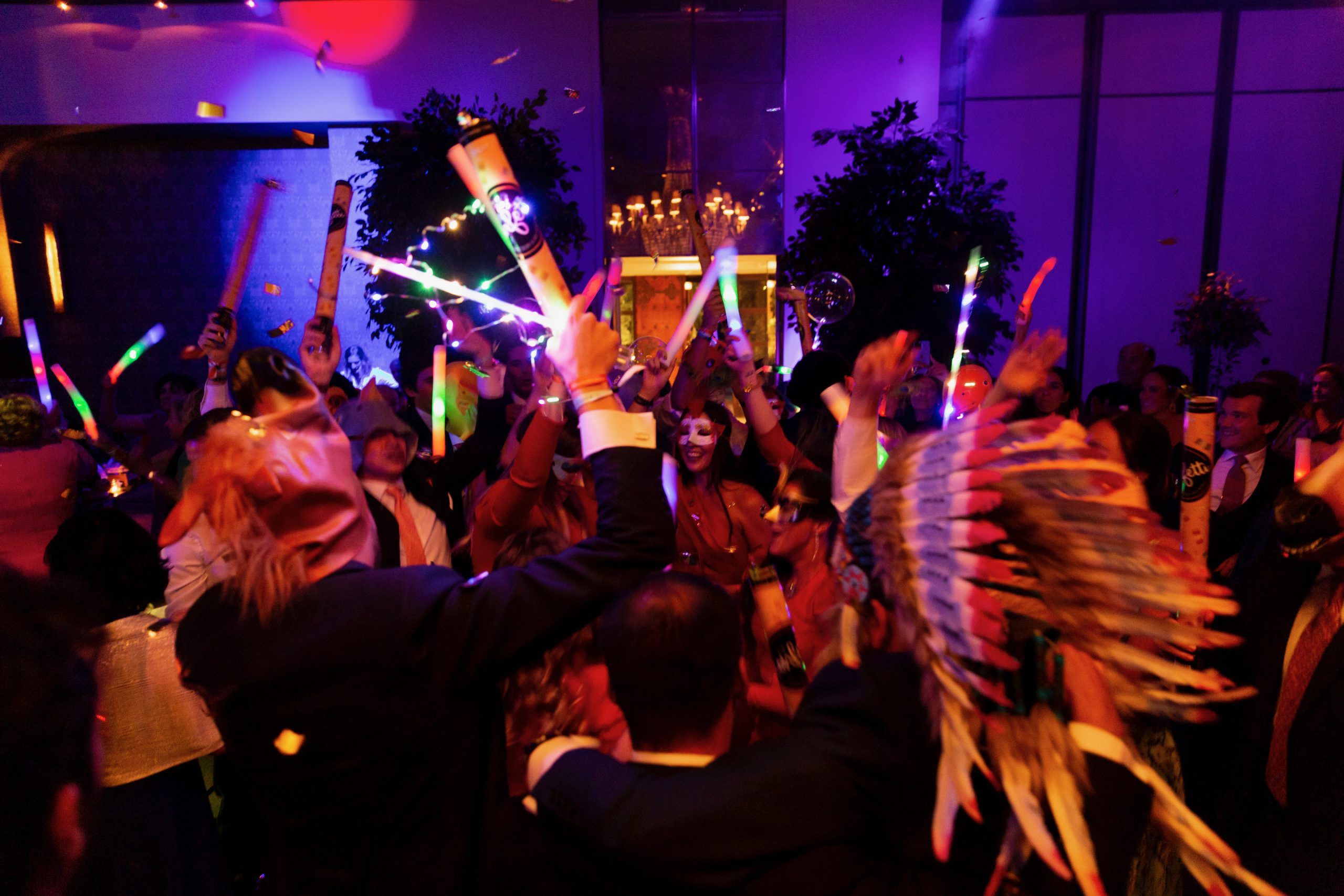 Pista de baile llena de invitados con barras luminosas de colores